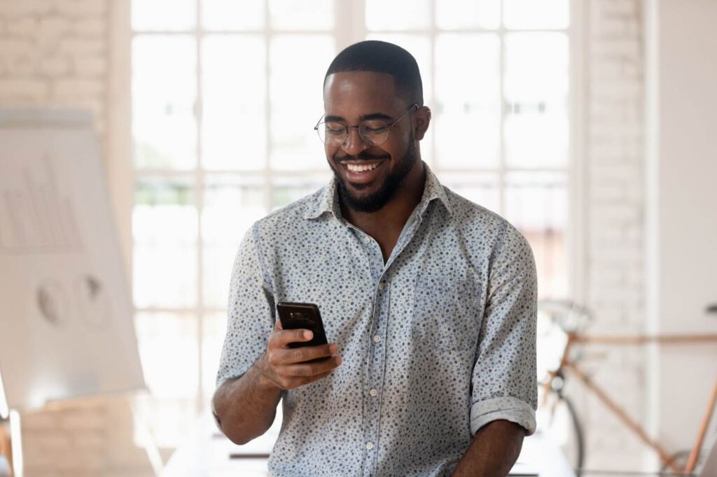 this is a picture of a man smiling at his phone. 